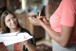 Garcom anotando pedido de cliente sorridente em restaurante demonstrando atendimento de qualidade