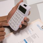 Pessoa calculando preco de produto ou servico com calculadora e documentos